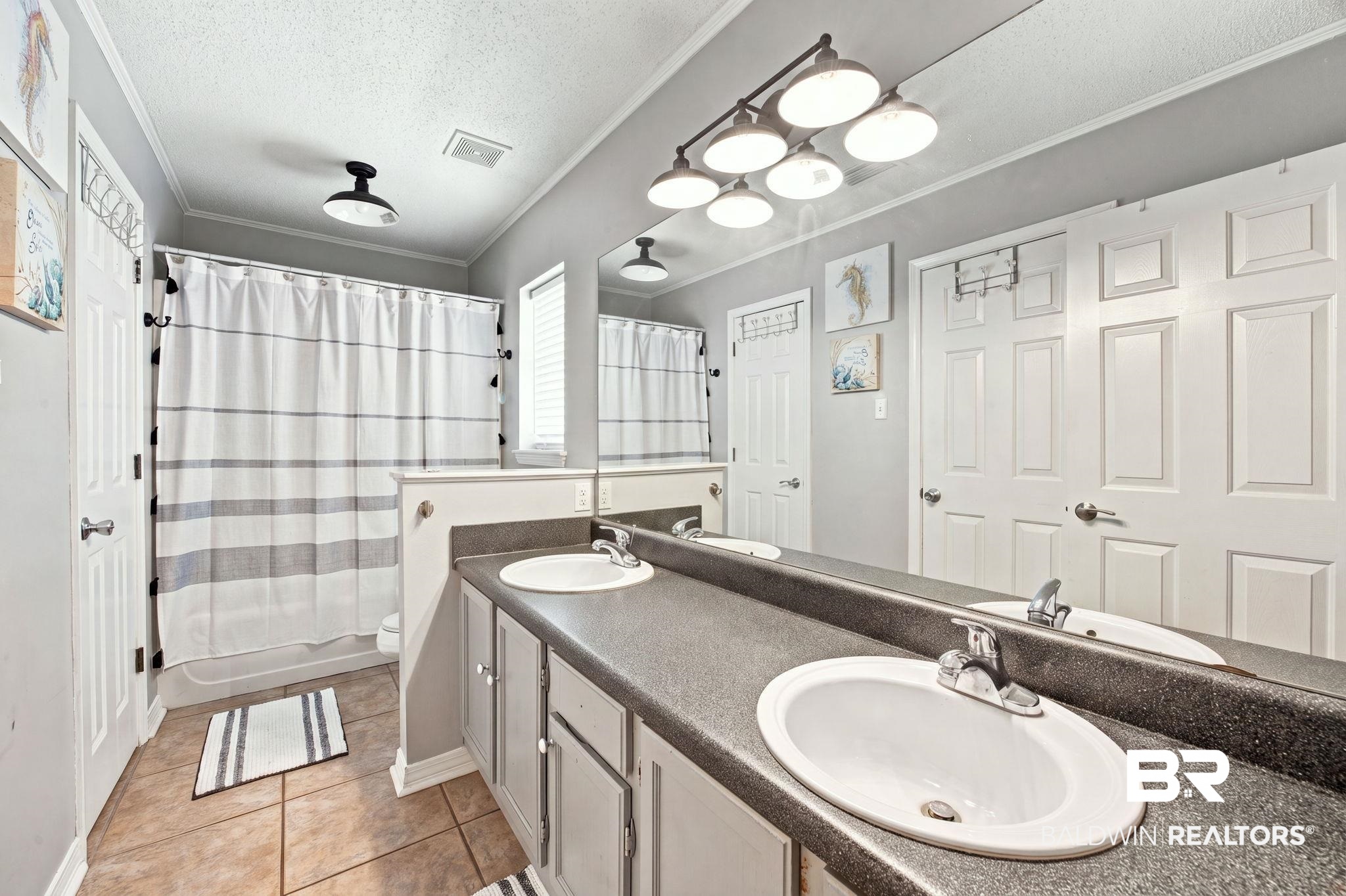 7577 Audubon Drive Foley, AL 36535 - Photo 18 of 33 Bathroom featuring a dual vanity with integrated sinks, a tub/shower combination, and tiled flooring