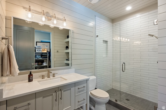 3 Carriagewood Cove, Unit 1088 Sandy, UT 84092 - Photo 47 of 79 Contemporary bathroom featuring a spacious glass-enclosed shower with subway tile surround, single vanity with integrated sink and stone countertop, shiplap wall finishes, and brushed nickel hardware