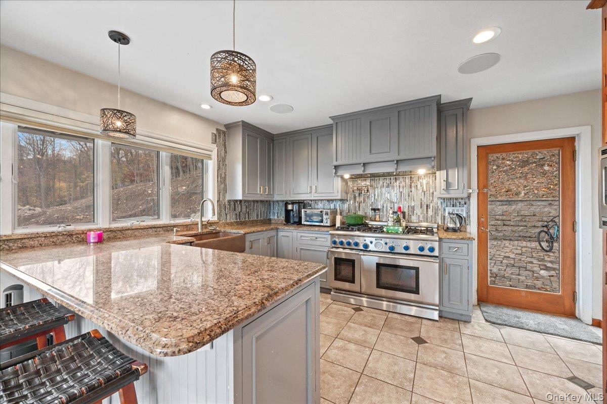 772 Rte 9W Nyack, NY 10960 - Photo 3 of 18 Kitchen featuring gray cabinets, double oven range, a peninsula, a kitchen bar, and hanging light fixtures