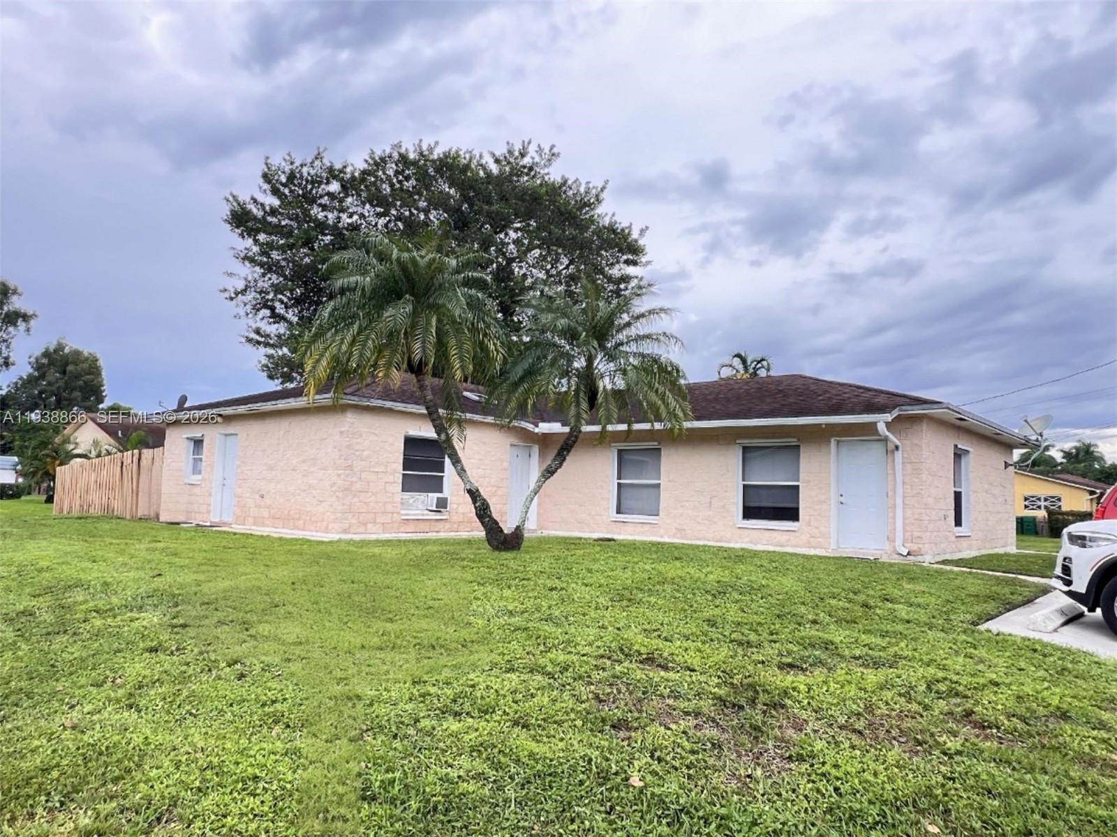 4865-4867 Southwest 65th Way, Unit AC Davie, FL 33314 - Photo 1 of 2 a white house with a small yard and large trees