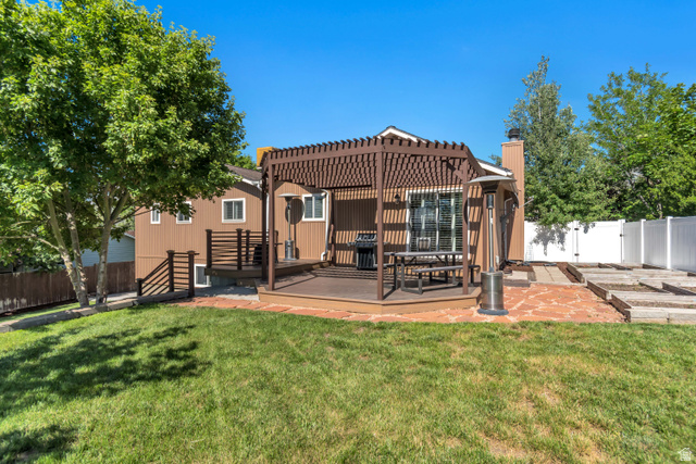 9832 Falconhurst Drive Sandy, UT 84092 - Photo 26 of 29 Expansive backyard featuring a wood-finish deck with a pergola, stone paver patio, and terraced landscaping