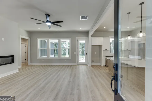 a view of an empty room with a window and a kitchen