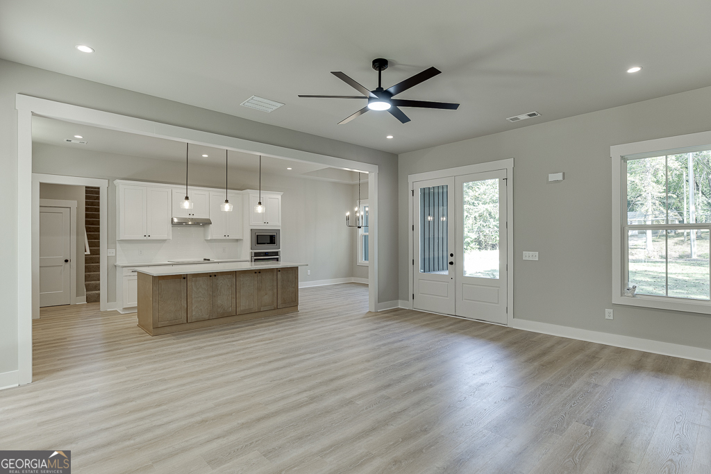 115 Rains Road Jefferson, GA 30549 - Photo 9 of 44 a large kitchen with kitchen island a island wooden floor stainless steel appliances and a window