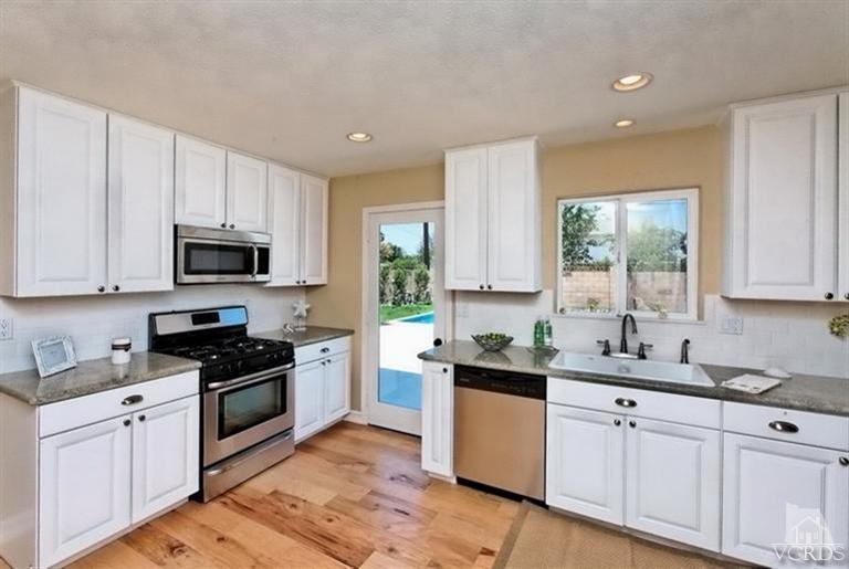 a kitchen with granite countertop white cabinets sink and stainless steel appliances