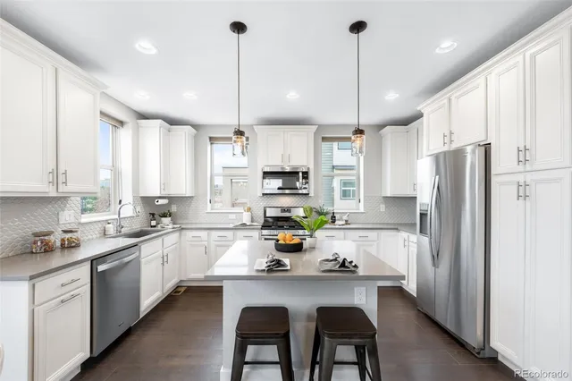 a kitchen with stainless steel appliances granite countertop a refrigerator a sink dishwasher a stove a kitchen island and chairs with wooden floor