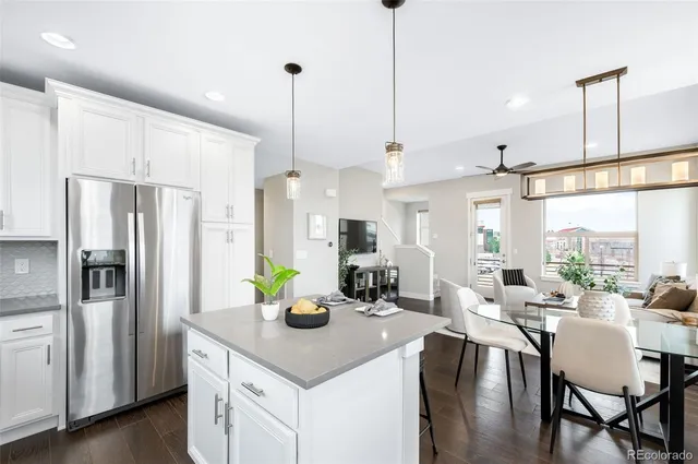 a kitchen with stainless steel appliances a dining table chairs and refrigerator