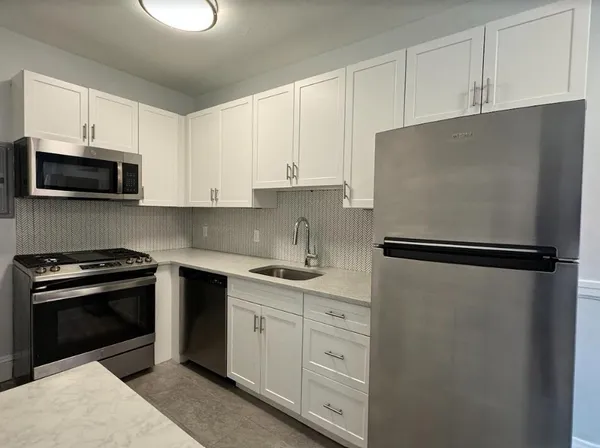 a kitchen with white cabinets and stainless steel appliances