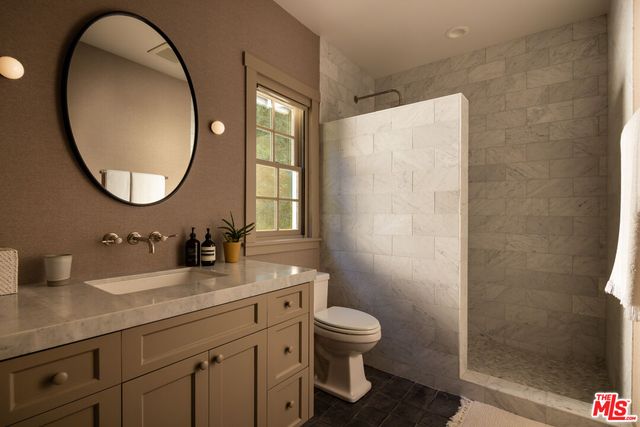 a bathroom with a granite countertop toilet sink and mirror