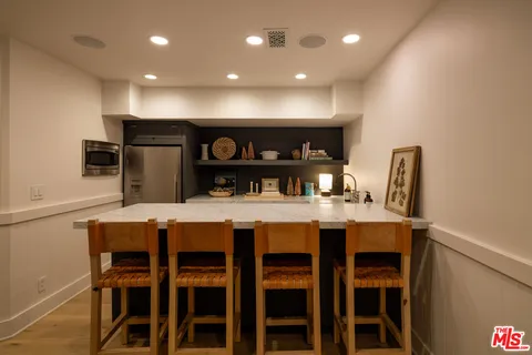 a kitchen with a dining table chairs and refrigerator