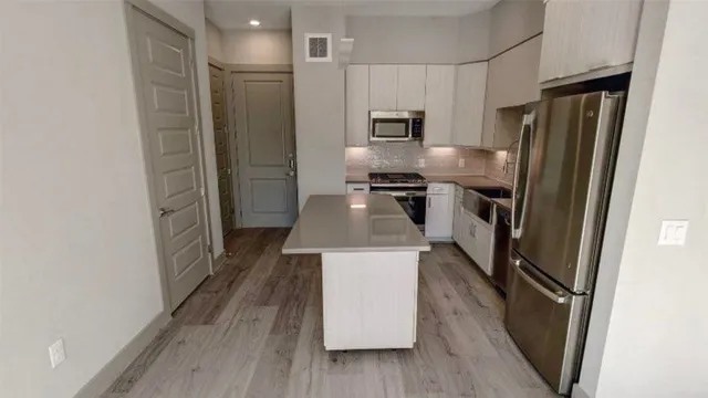 a kitchen with a refrigerator a sink and wooden floor