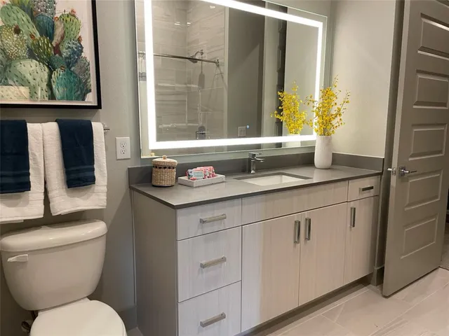 a bathroom with a granite countertop toilet sink and mirror