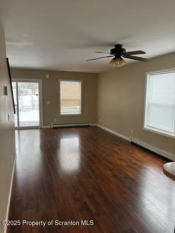 a view of empty room with wooden floor and fan