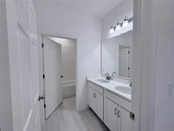 a spacious bathroom with a double vanity sink a mirror and a shower