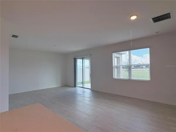 a view of an empty room with a window and wooden floor