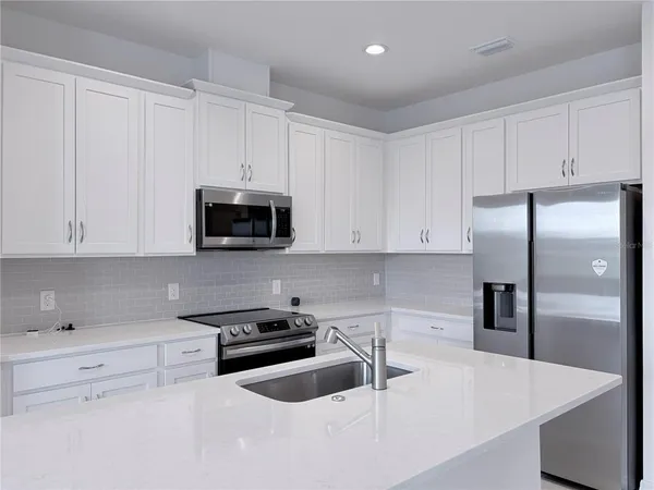a kitchen with granite countertop white cabinets and stainless steel appliances