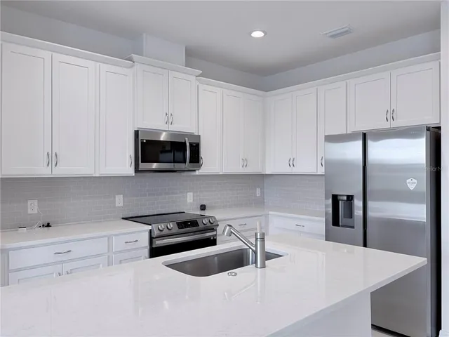 a kitchen with granite countertop white cabinets and stainless steel appliances