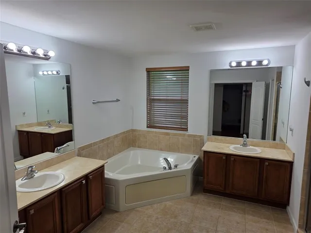 a bathroom with a tub a sink and a mirror
