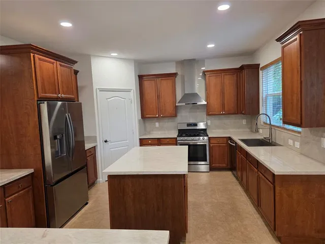 a kitchen with kitchen island granite countertop wooden cabinets a refrigerator a sink a stove a washer dryer and cabinets