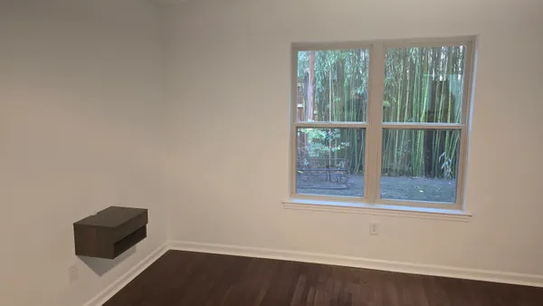 an empty room with wooden floor and windows