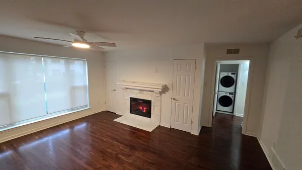 an empty room with wooden floor fireplace and windows