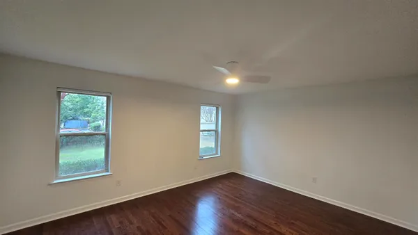 an empty room with wooden floor and windows