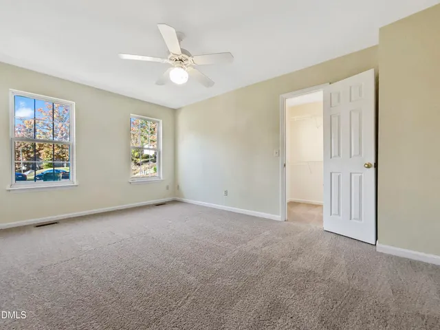 an empty room with windows and fan