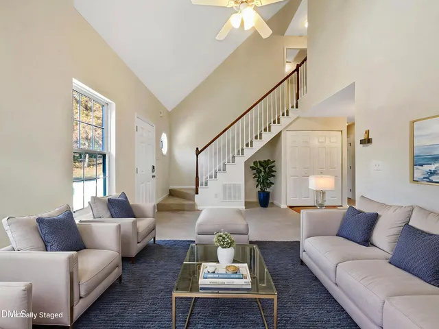 a living room with furniture couches and a dining table with wooden floor