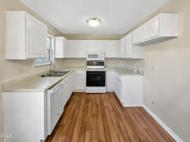 a kitchen with a sink a stove cabinets and a wooden floor