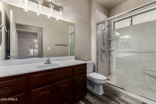 a bathroom with a granite countertop sink toilet a mirror and shower