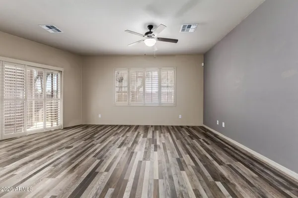 a view of an empty room with wooden floor and a window