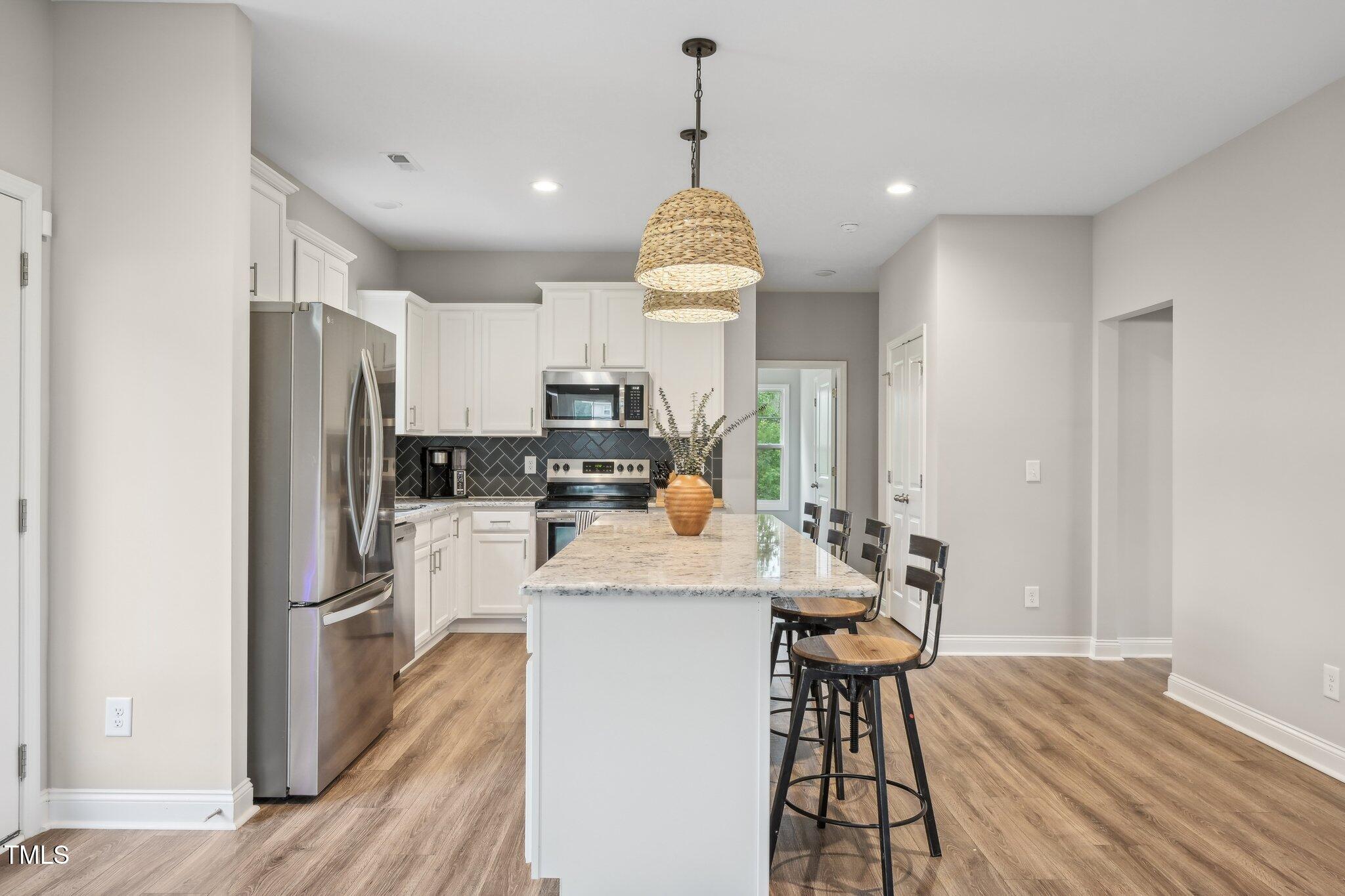 195 Solomon Drive Cameron, NC 28326 - Photo 12 of 46 a kitchen with stainless steel appliances kitchen island granite countertop a refrigerator a stove top oven a sink dishwasher and white cabinets with wooden floor