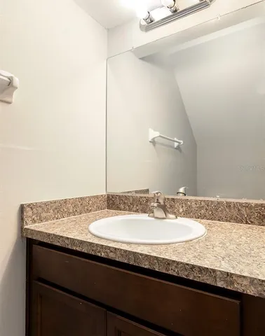 a bathroom with a granite countertop sink and a mirror