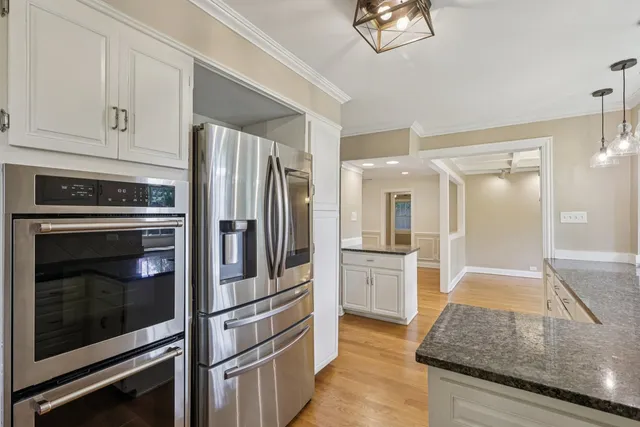 a kitchen with granite countertop a sink stainless steel appliances white cabinets and a window