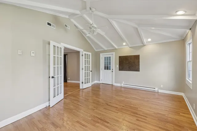 a view of an empty room with window and wooden floor