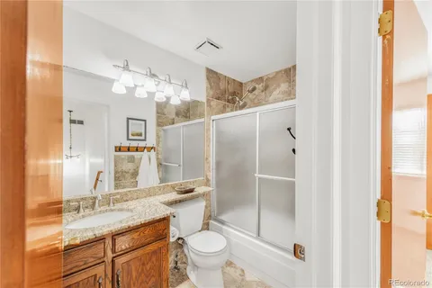 a bathroom with a granite countertop sink toilet and shower