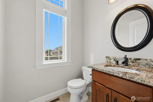 a bathroom with a granite countertop toilet a sink and a mirror