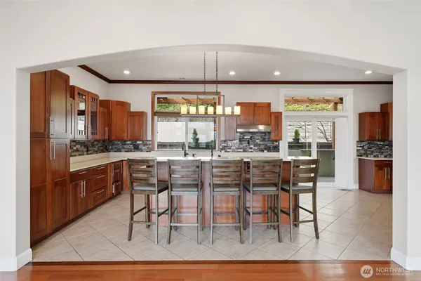 a kitchen with stainless steel appliances kitchen island granite countertop a table chairs sink and cabinets