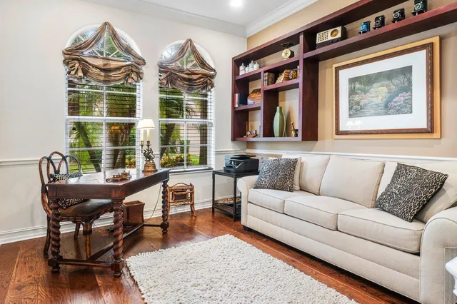 a living room with furniture a floor to ceiling window and wooden floor