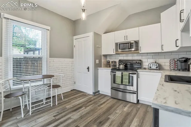 a kitchen with granite countertop a stove a sink and a refrigerator