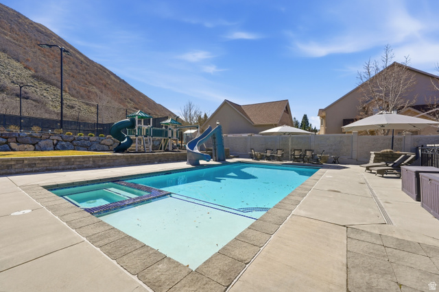 714 Draper Heights Way Draper, UT 84020 - Photo 5 of 88 Integrated pool / hot tub featuring a water slide, a patio area, and a fenced backyard