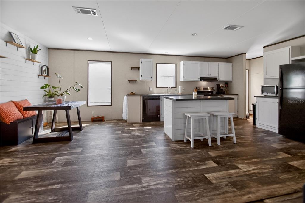 2857 Hickory Street Bunnell, FL 32110 - Photo 4 of 22 a kitchen with stainless steel appliances granite countertop a stove top oven a sink dishwasher a dining table and chairs with wooden floor