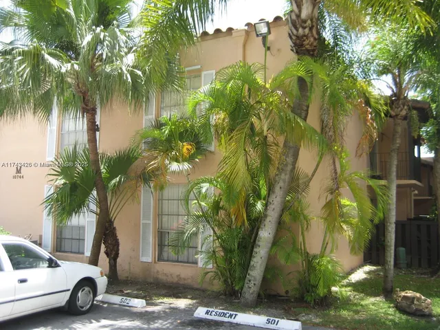 a view of a street with a building and palm trees