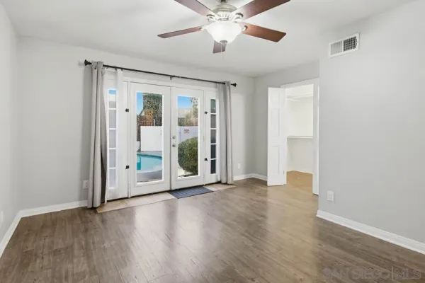 an empty room with wooden floor ceiling fan and windows in a room