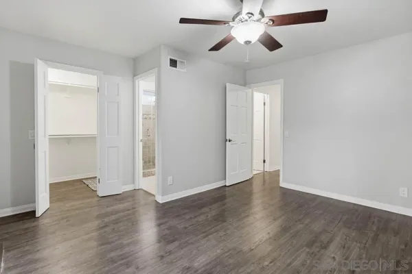 an empty room with wooden floor fan and windows