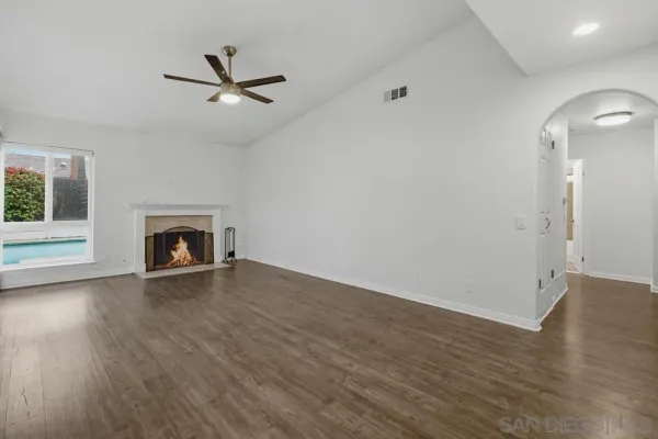 an empty room with wooden floor fireplace and windows