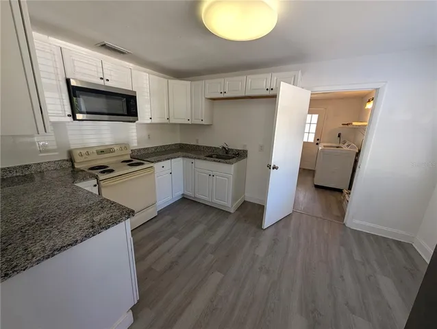 a kitchen with granite countertop a stove a sink and a microwave
