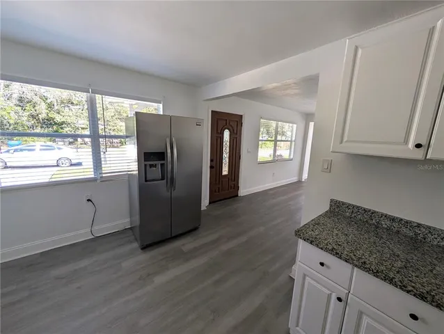a kitchen with granite countertop stainless steel appliances a refrigerator cabinets and wooden floor