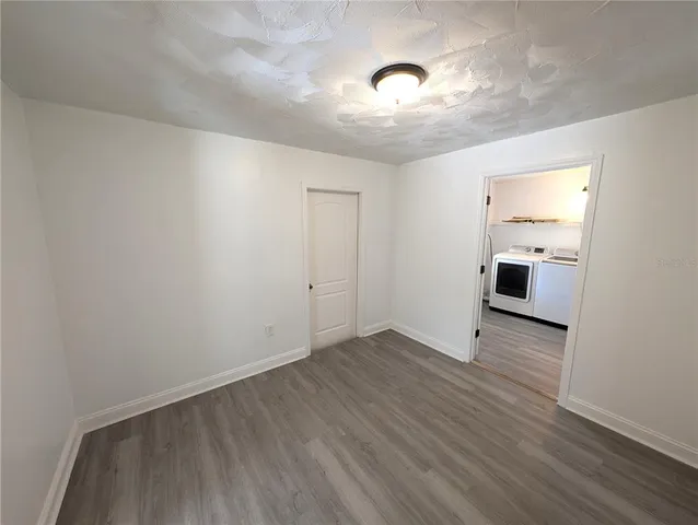 an empty room with wooden floor cabinet and windows