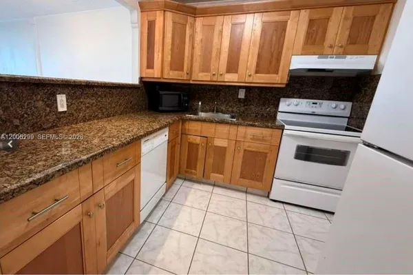 a kitchen with granite countertop a stove a sink and a microwave