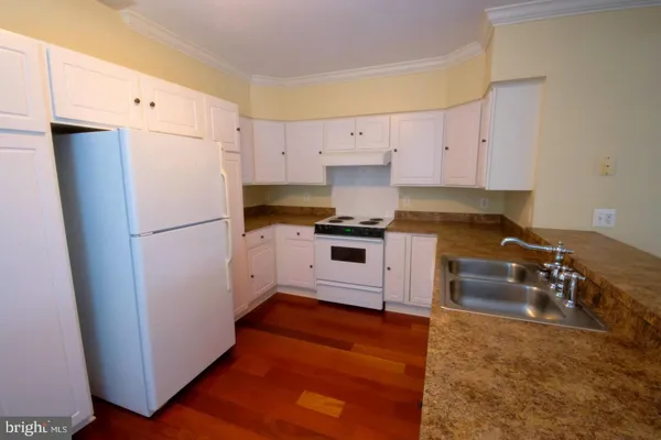 a kitchen with granite countertop a refrigerator a sink and white cabinets